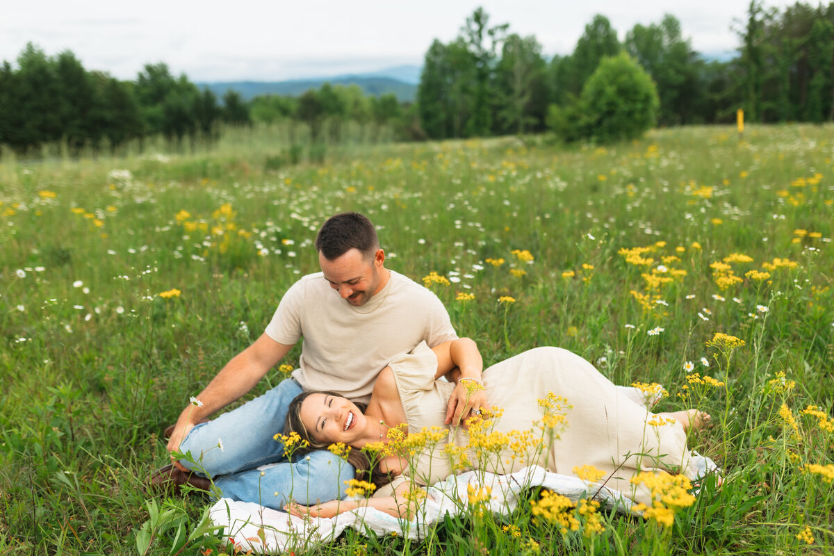 a pregnant woman laying with her head in her husband's lap
