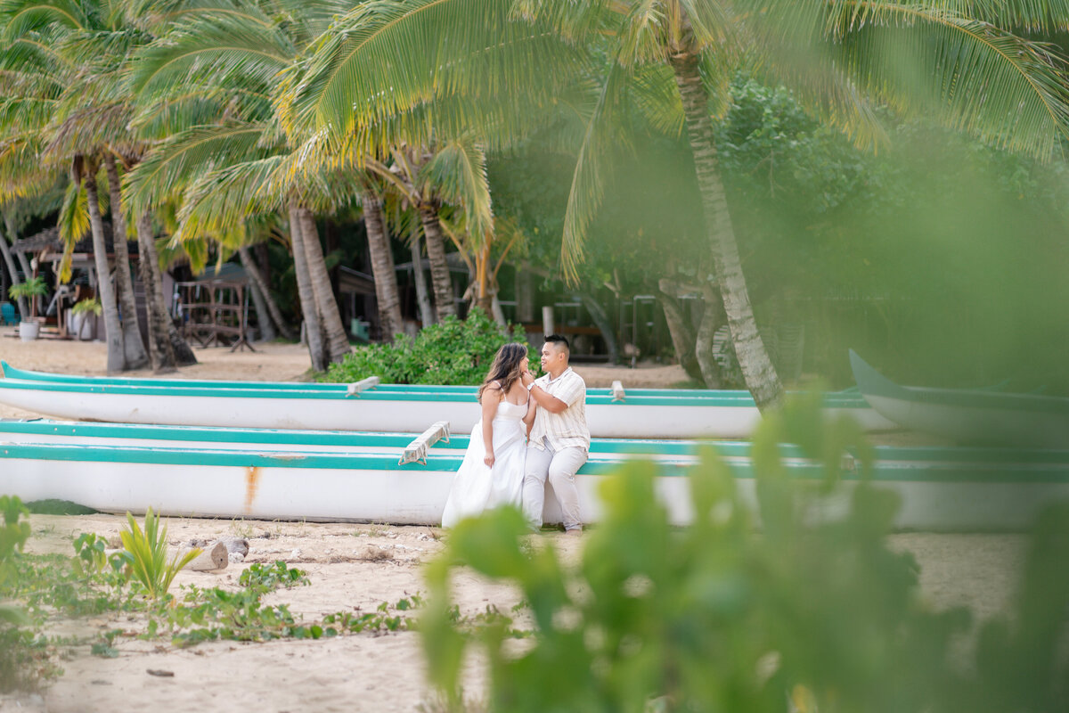 Oahu Hawaii Elopement Asian couple at Secret Island Beach during sunset with boats and canoes.