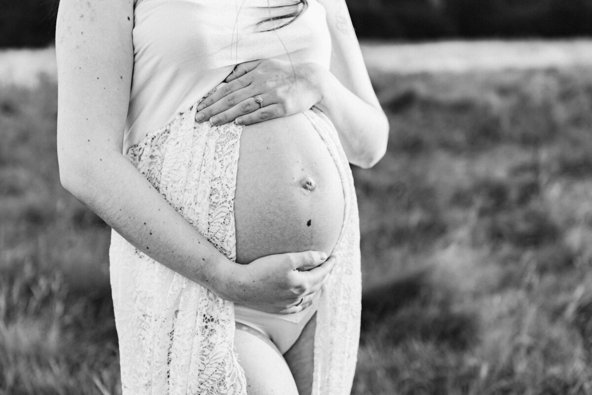 A black and white close up of a pregnant bump in maternity photoshoot in Billingshurst