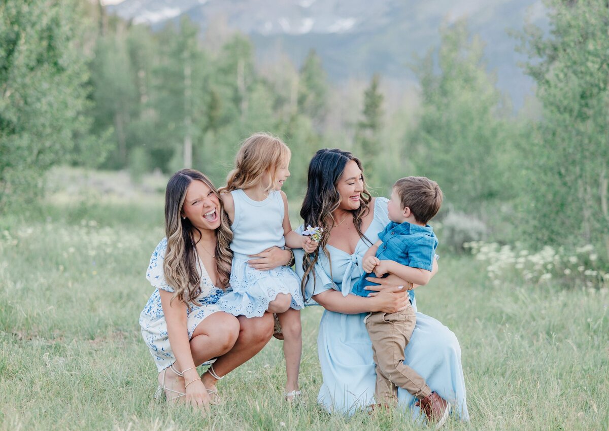 Toddler boy and girl laugh with their moms in a field of wildflowers all in blue