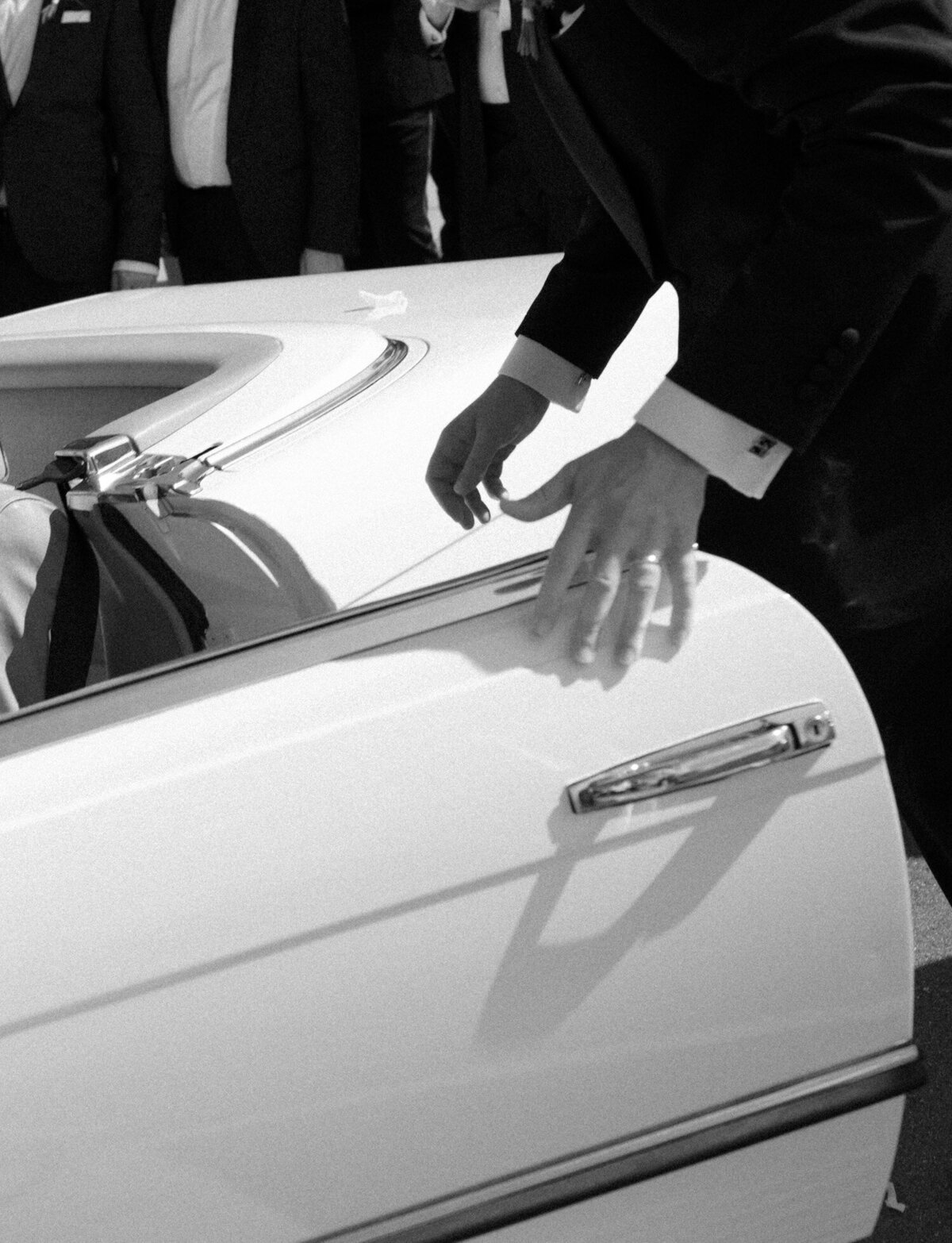 a groom closes the door of a vintage mercedes convertible wedding car in Detroit, Michigan