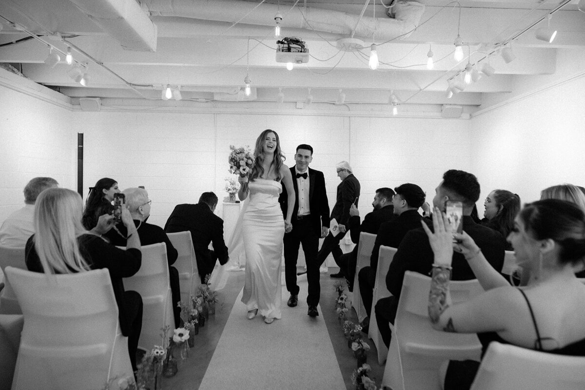 Bride and groom walk happily down the aisle of their small elopement.  
