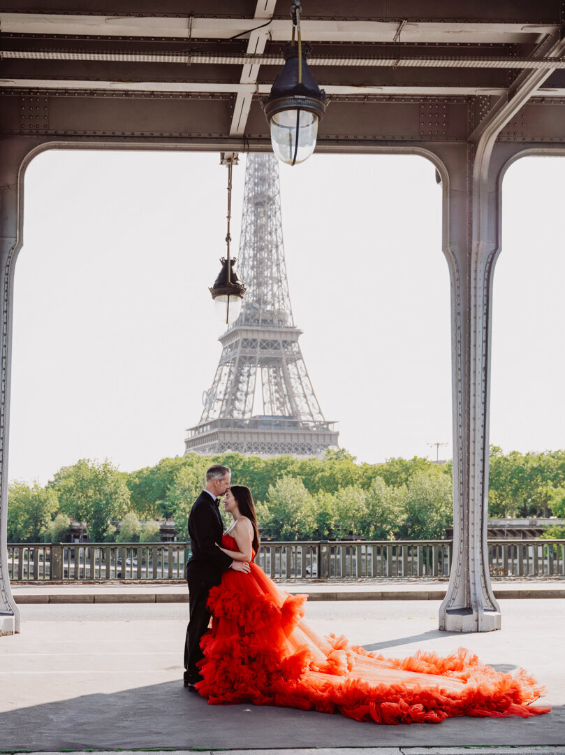 Romantic couple pose Bir Hakeim Bridge, red princess dress, Eiffel Tower view, Paris photography