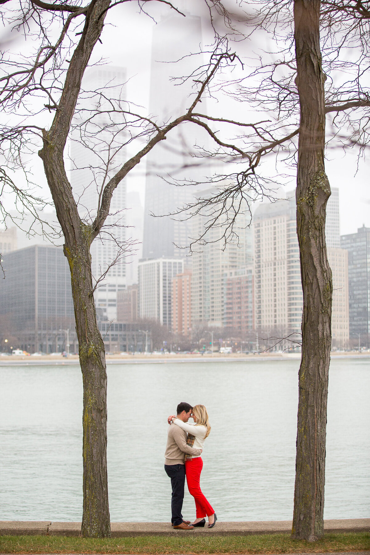 A romantic engagement photo, set against the Chicago skyline, at Olive Park