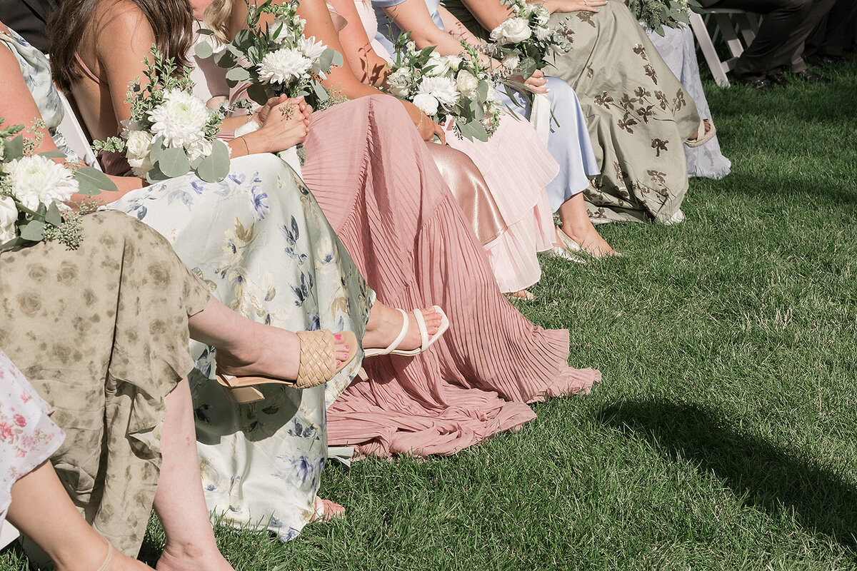 bridesmaids dresses and shoes as they sit during the wedding ceremony