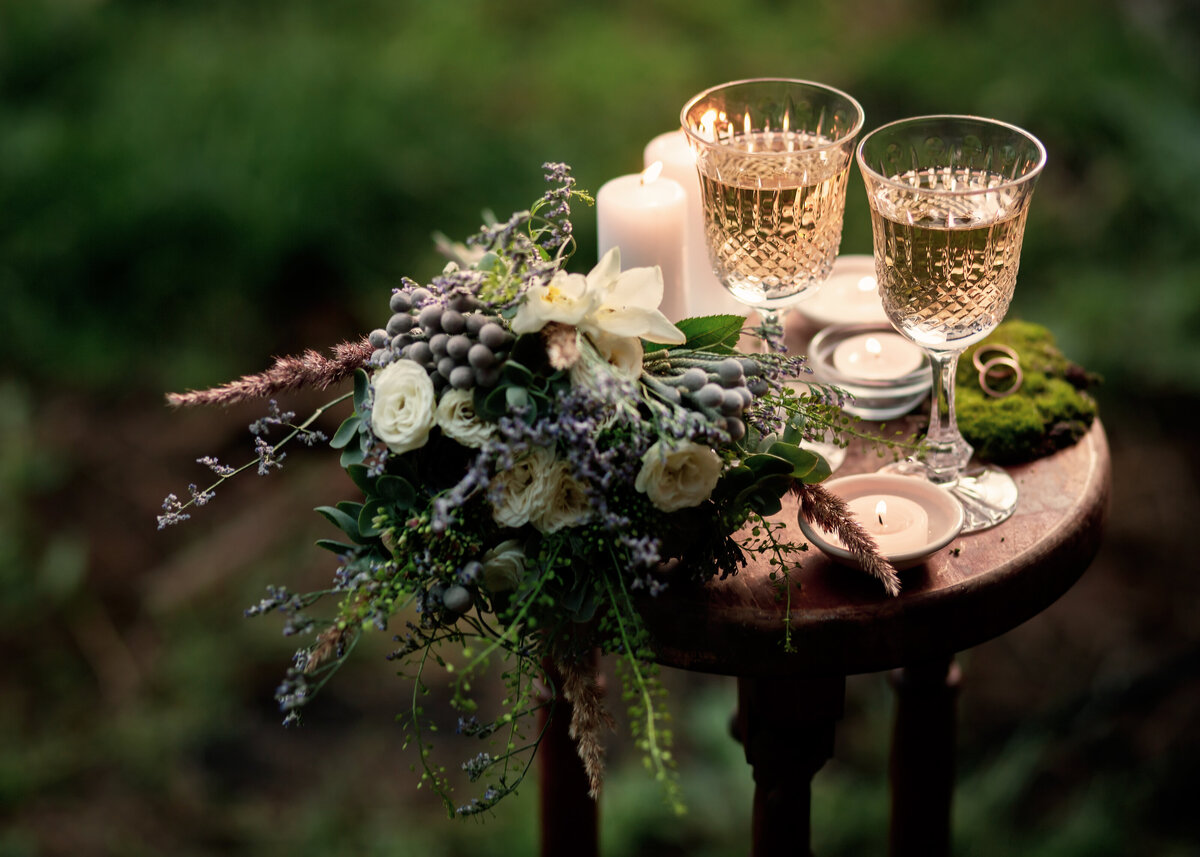 Vintage wedding background with bouquet, wine glasses and candles outdoors