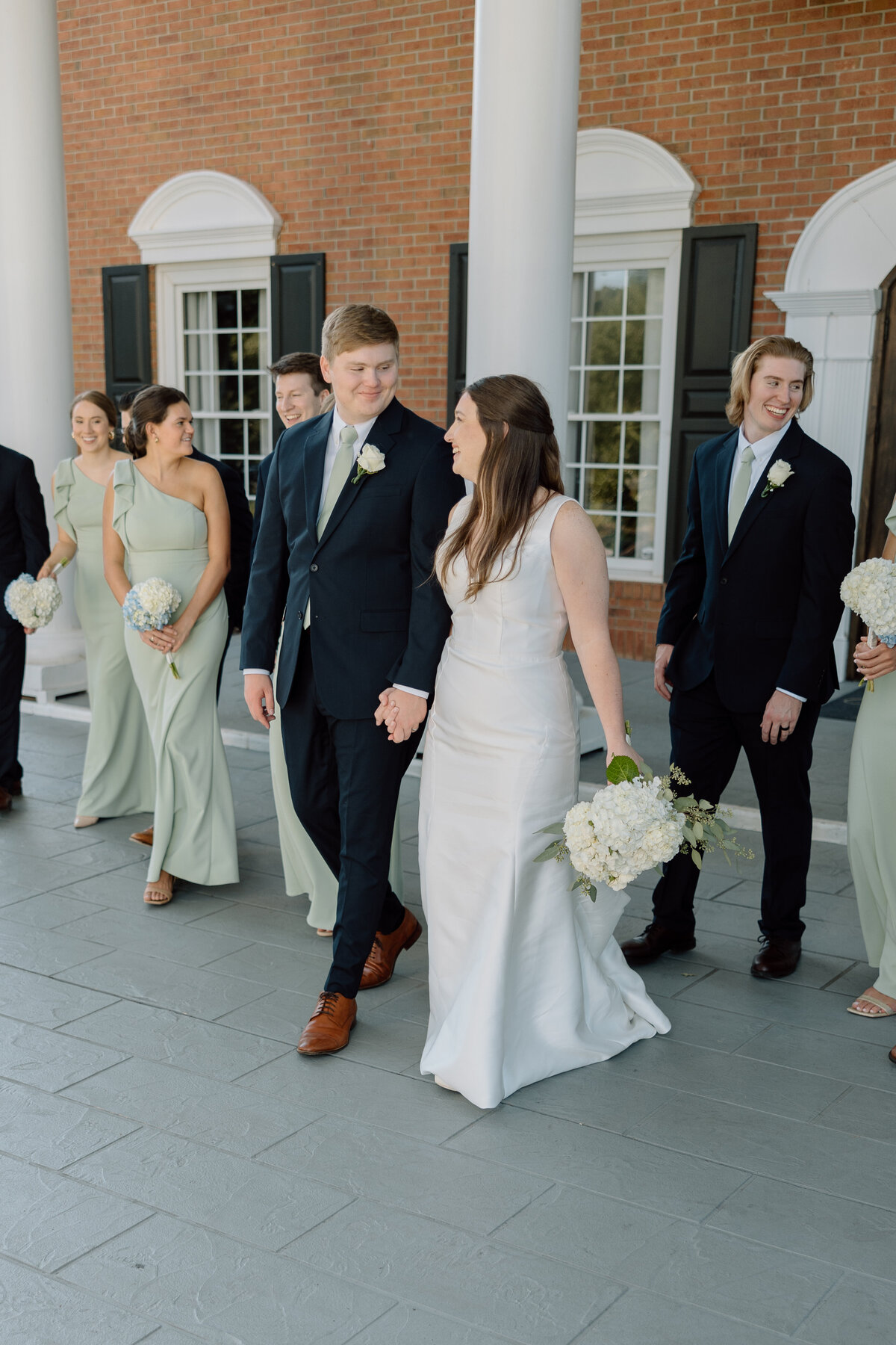 Bride and groom walk hand in hand with their bridal party