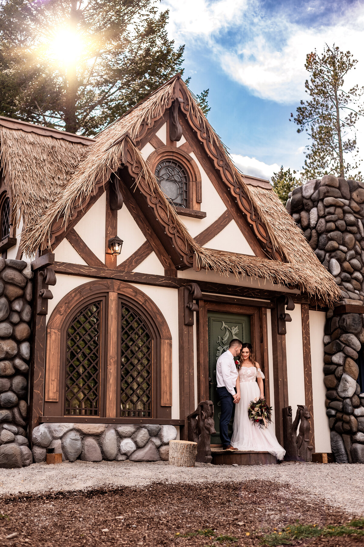Wedding couple poses in from of Snow Whites cottage at Charmed Resorts