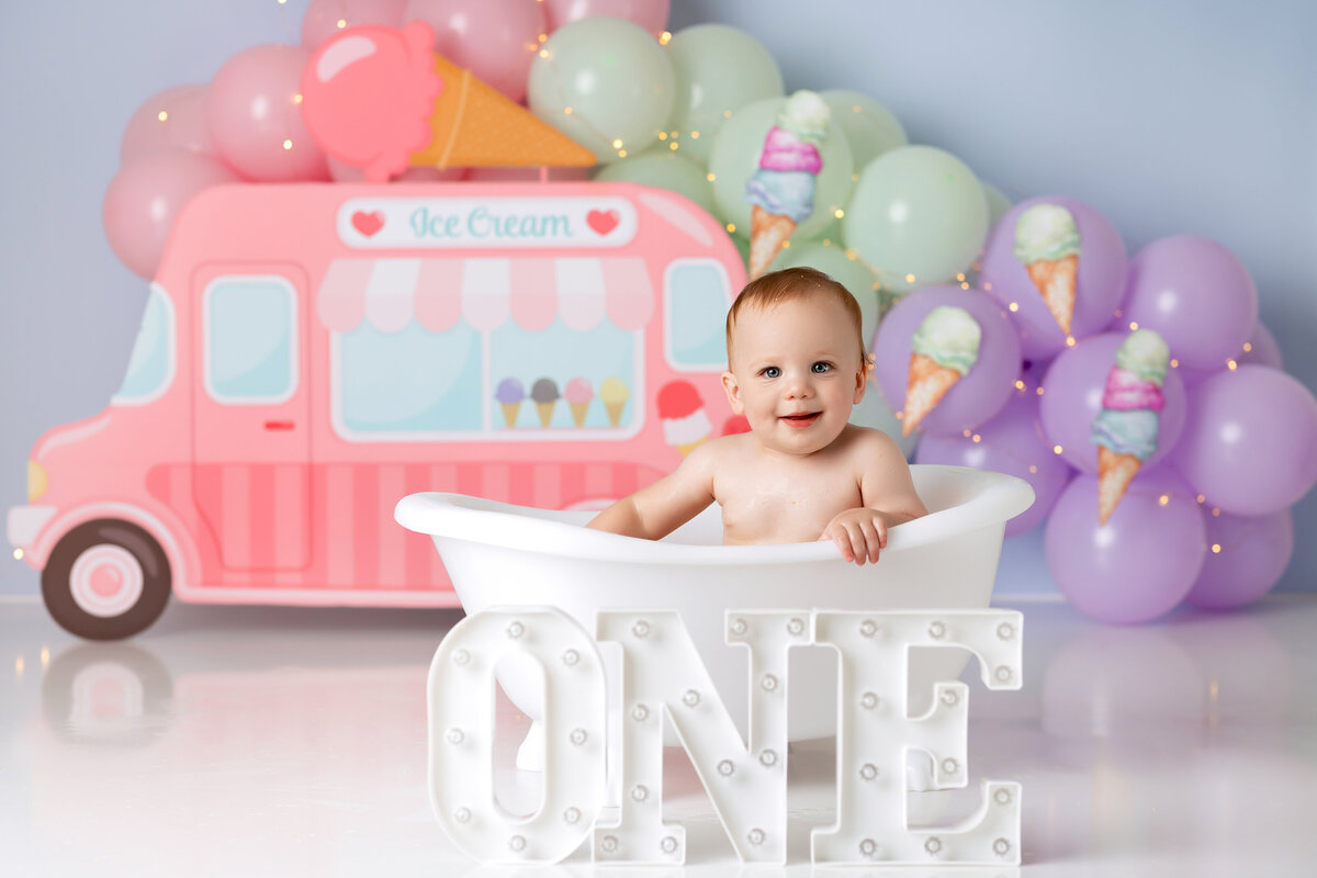 One year old Tampa baby enjoying a personalized luxury cake smash session with sweet one decorations