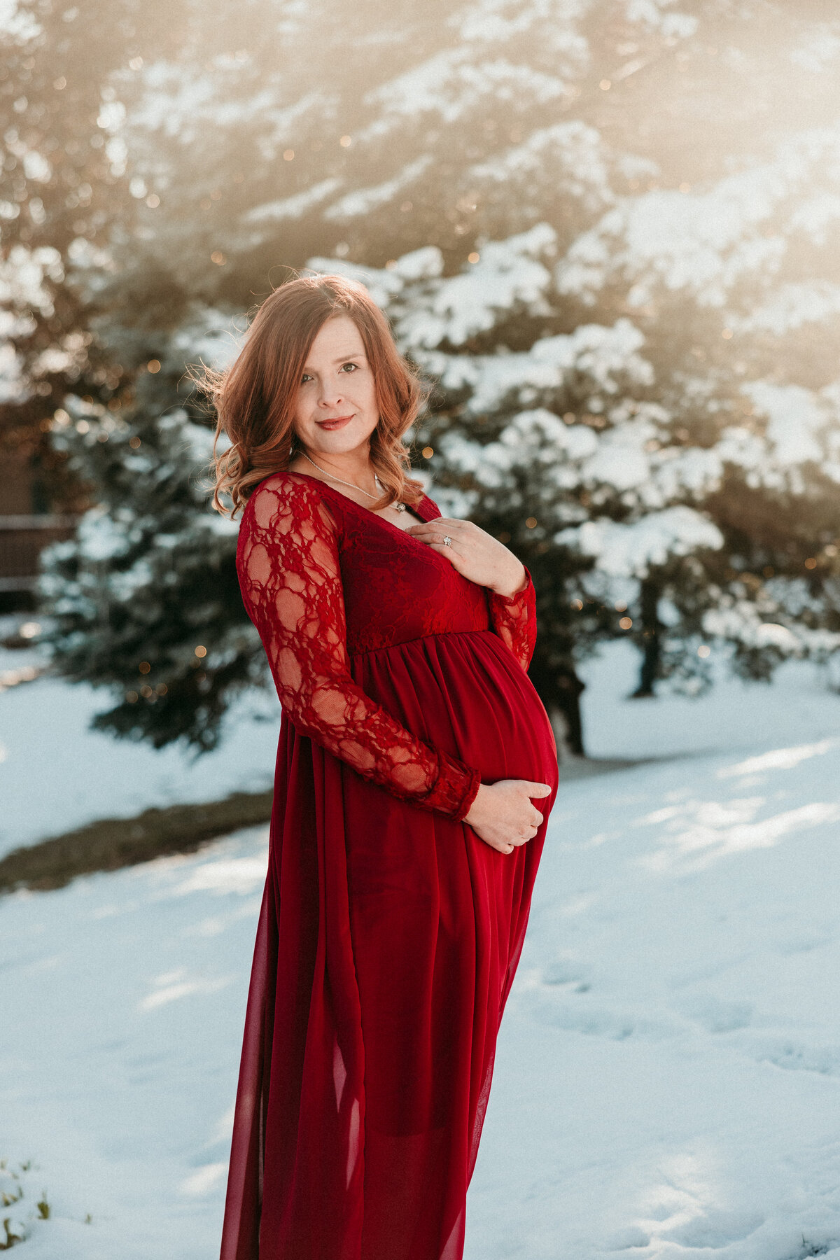 Pregnant mother poses in the snow in a small park in historic downtown St. Charles Missouri.