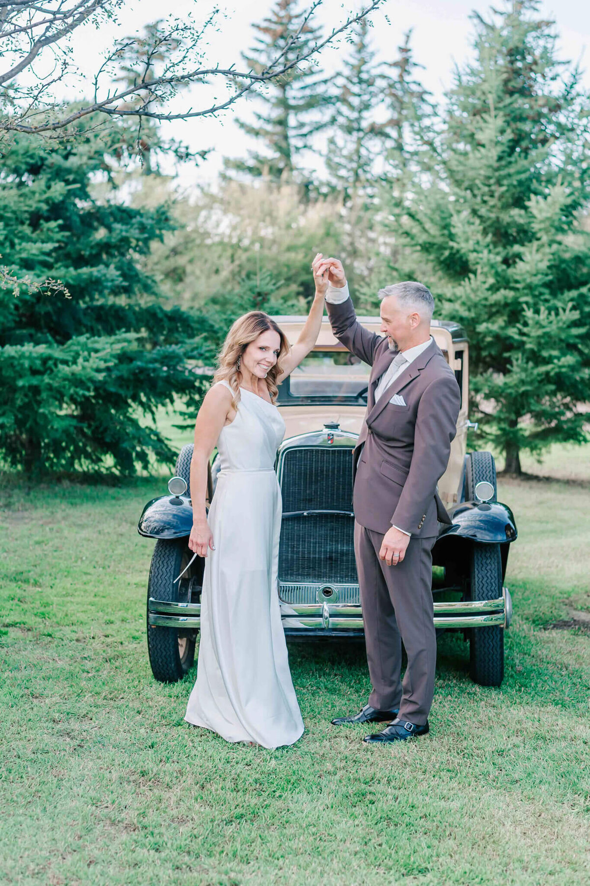 Groom holding brides hand and spinning her slowly in a circle.