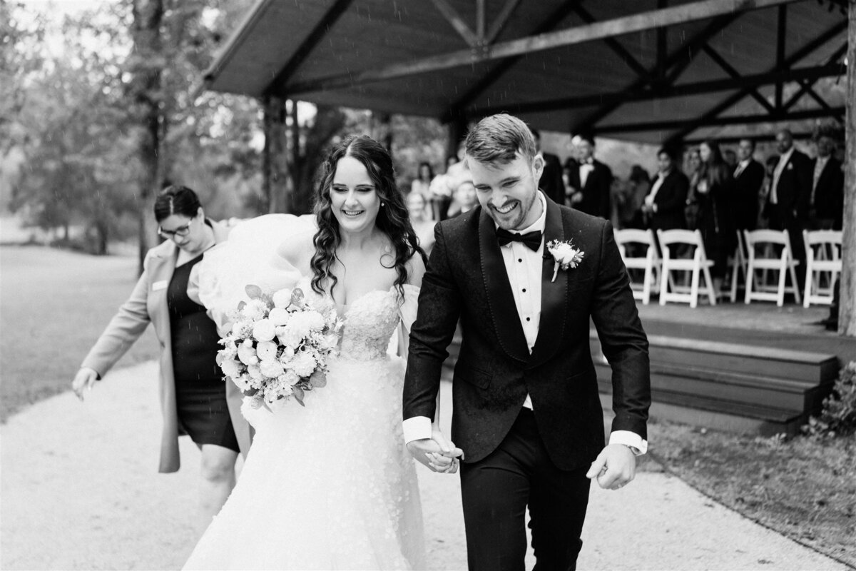 The newlyweds share a tender kiss as they exit the ceremony, radiating love and joy in their post-nuptial bliss.