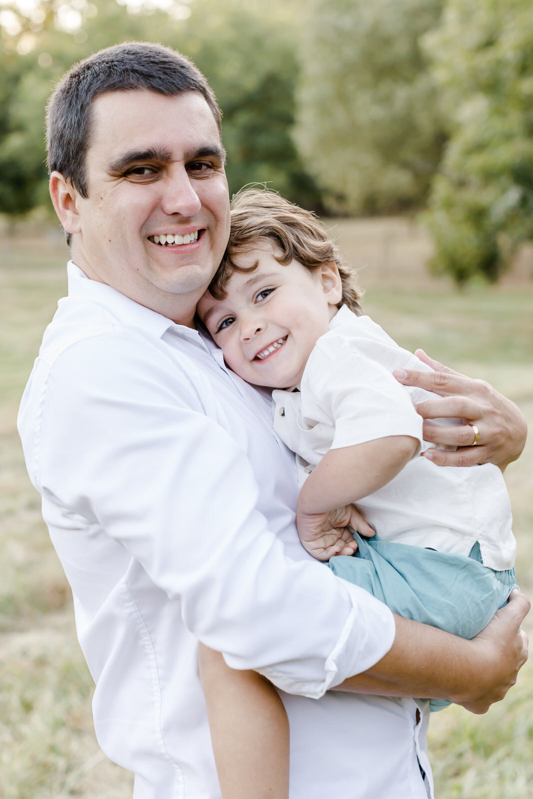 Dad holds and hugs young son as they smile at a family photo session