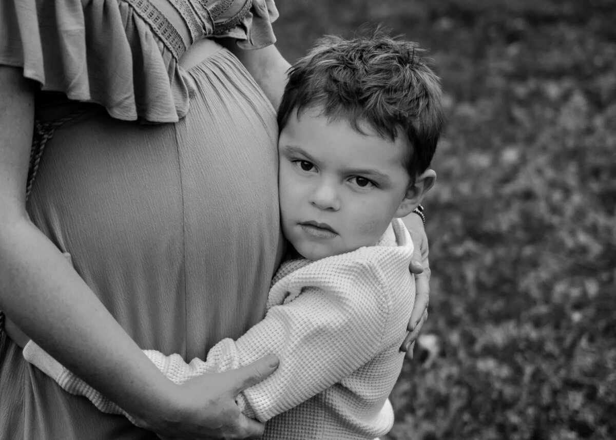 Pittsburgh maternity photographer captures touching moment of a pregnant woman embracing young boy in black and white photo.