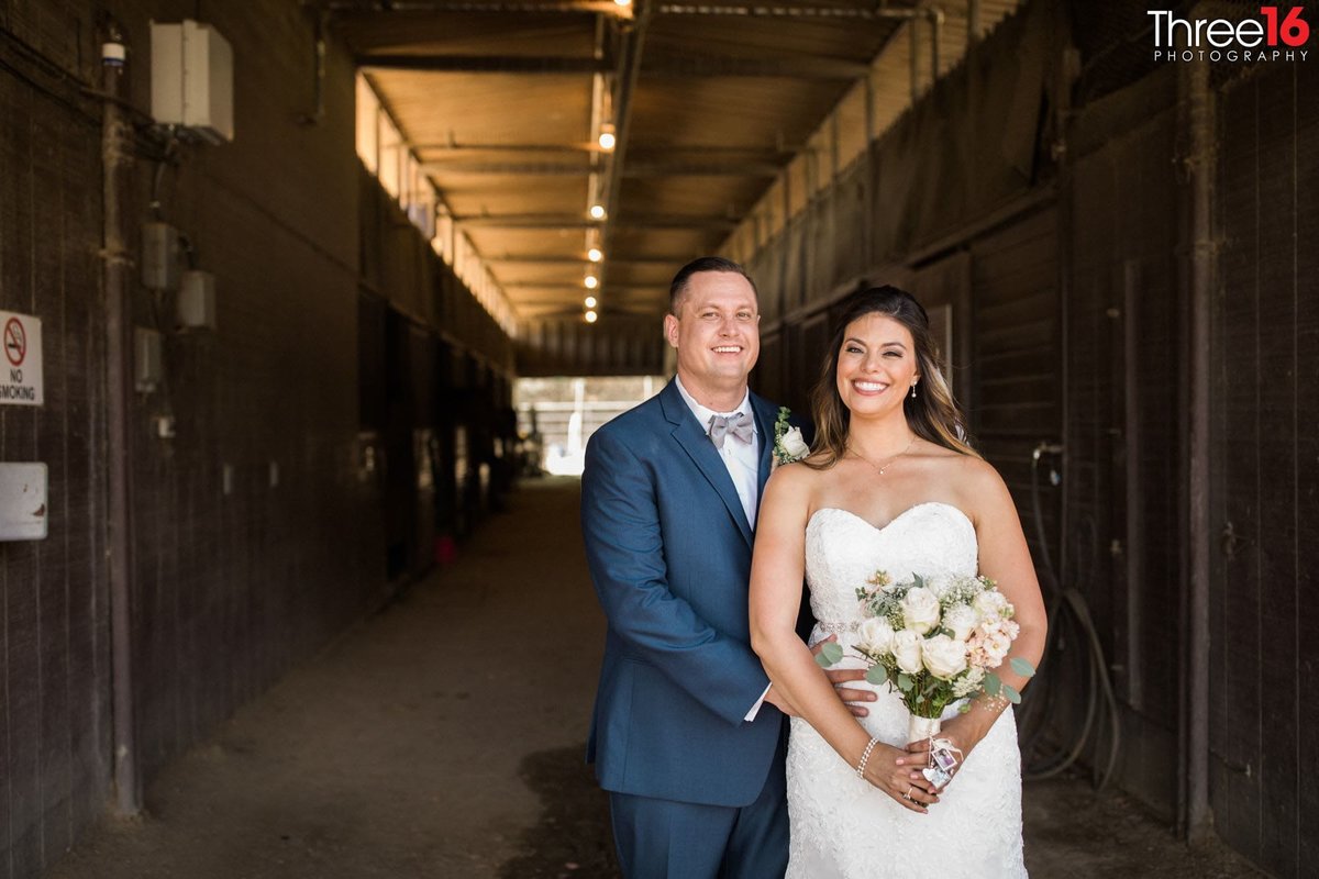 Bride and Groom pose inside the horse stable area