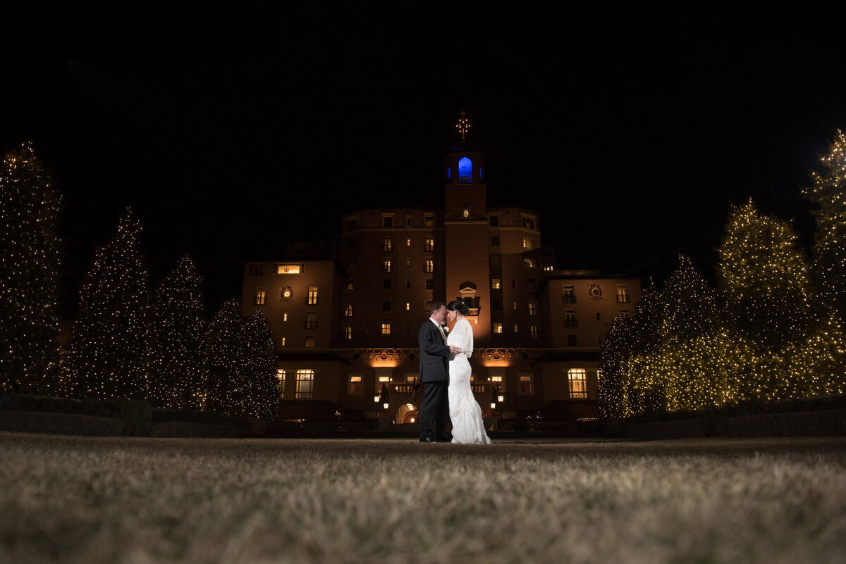 Night time photograph of couple hugging on the front lawn in front of the Broadmoor Hotel