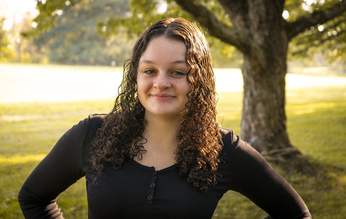 Warm photo of a young woman in front of a tree