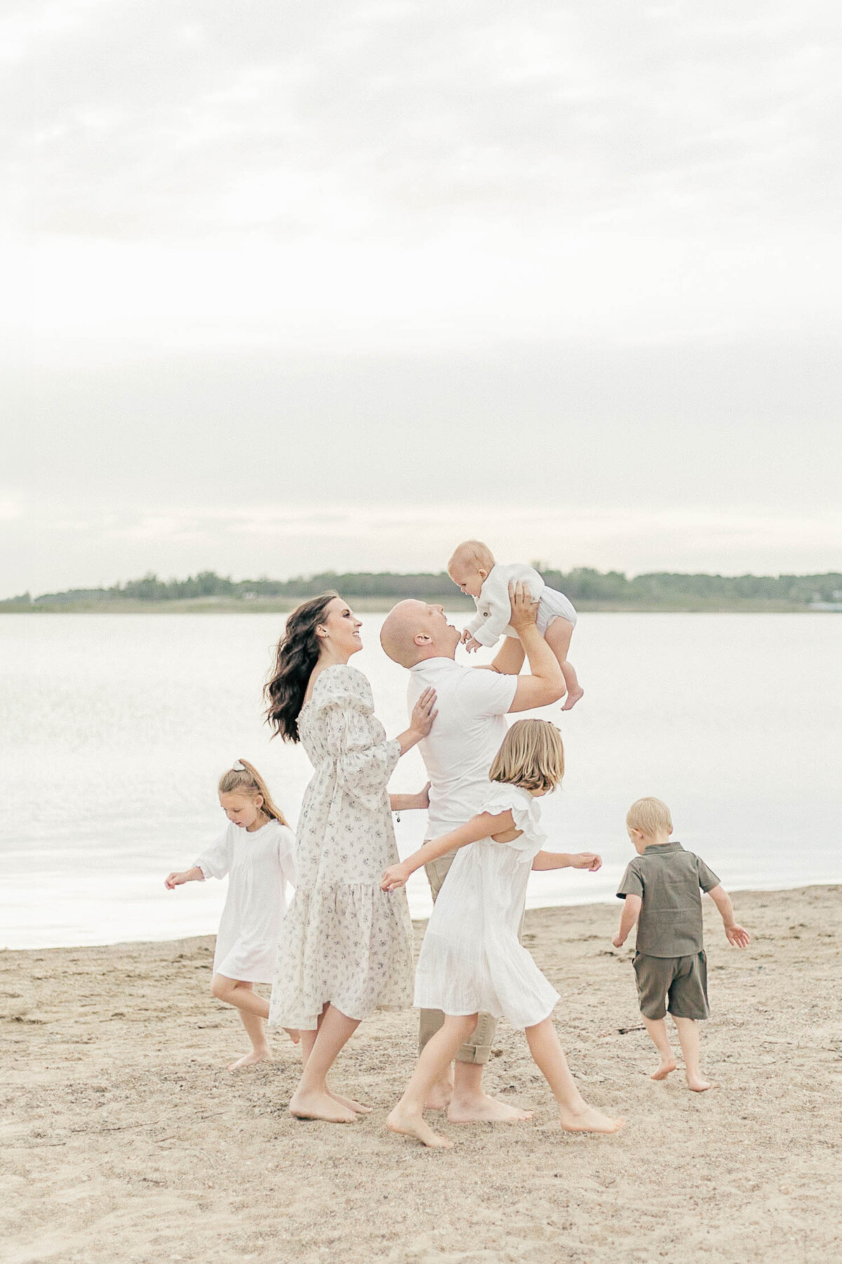Family picture of a family of six playing joyfully on the shore of a Kansas City lake