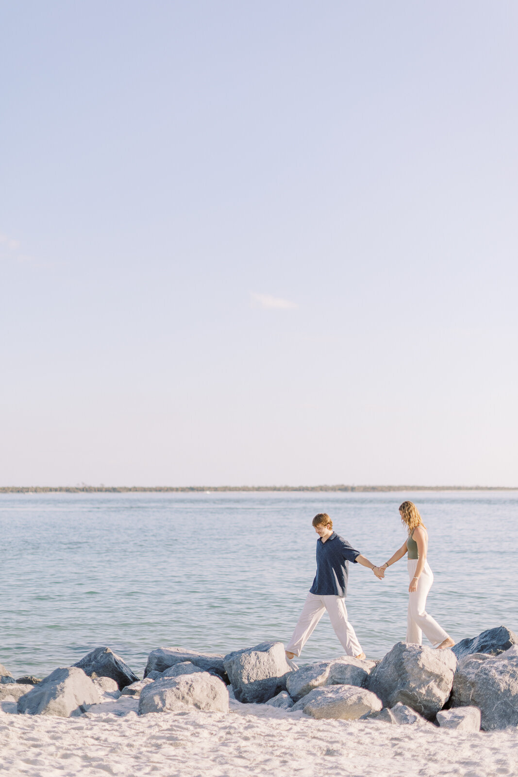 Couple walks together on beach for engagement shoot