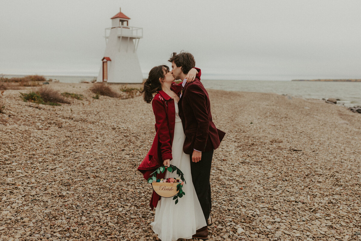 bride and groom kissing on pebble beach