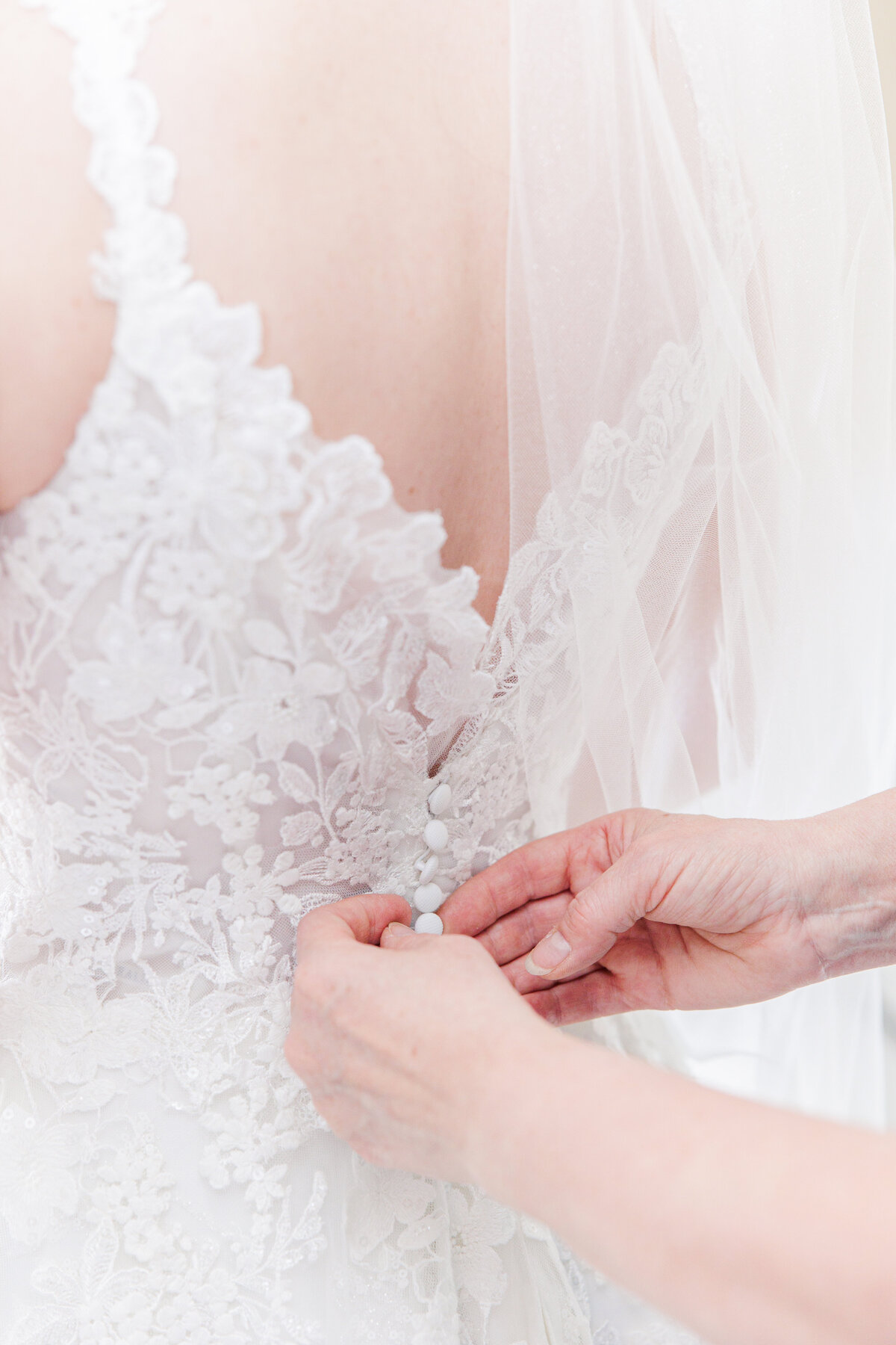 Close up of mother of the bride buttoning the wedding dress during Boston wedding portraits