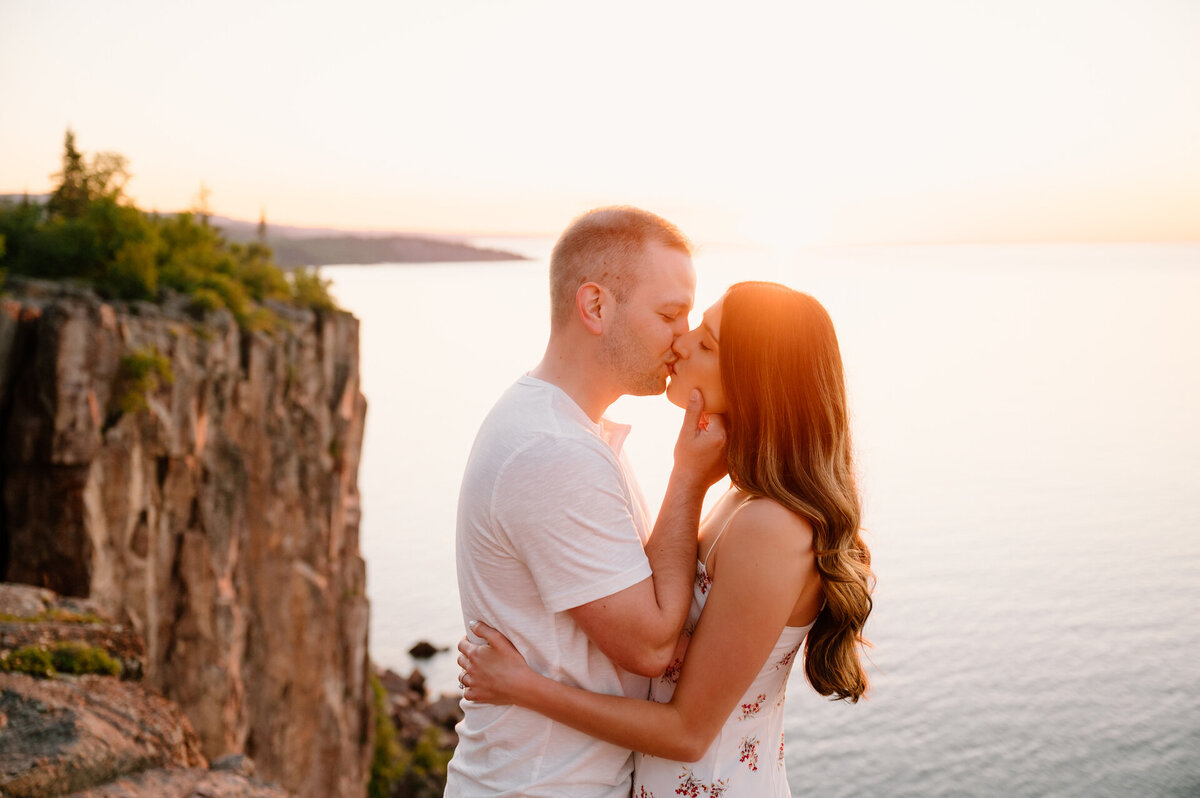 engaged couple kissing at sunset