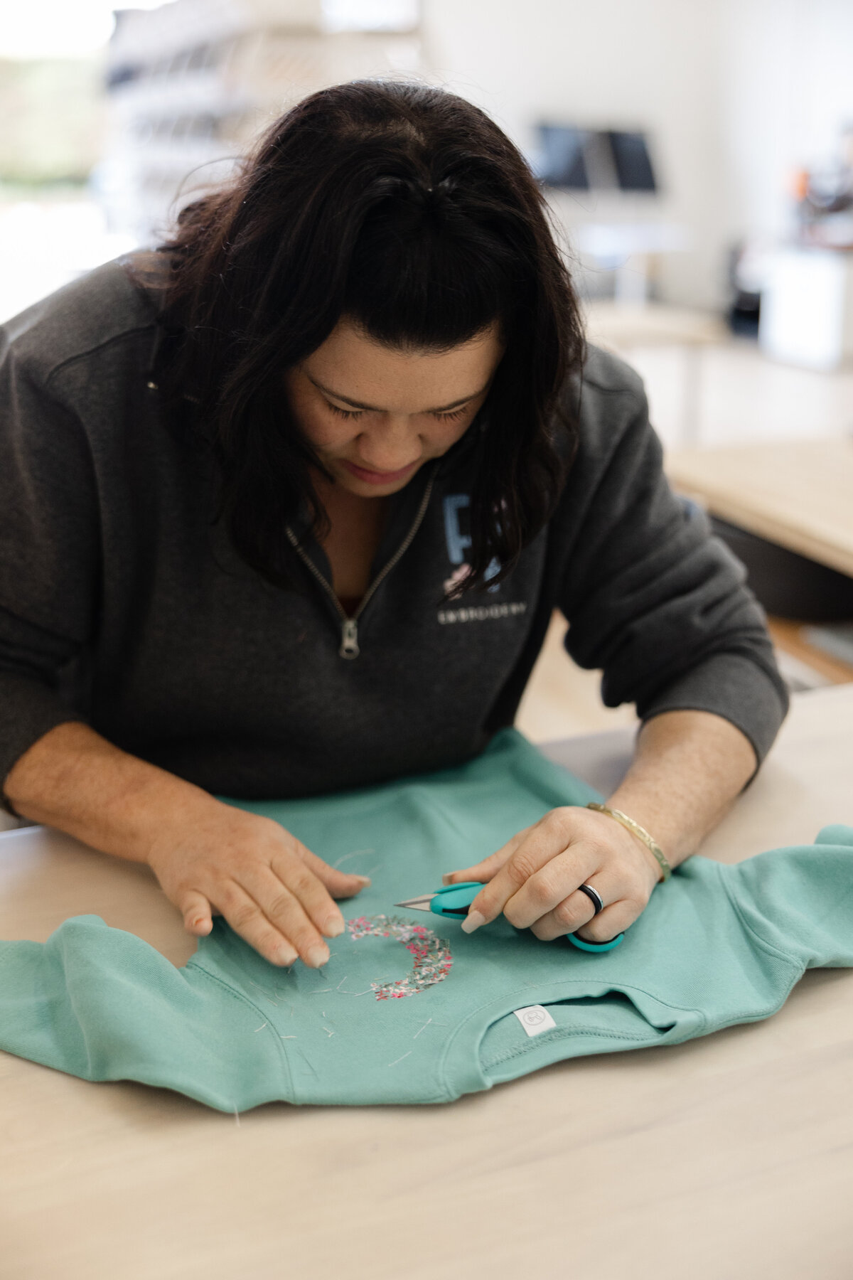 Woman with dark hair cutting fabric at a studio table. Photograph by Yucaipa branding photographer Kaitlyn Dawn Photography.