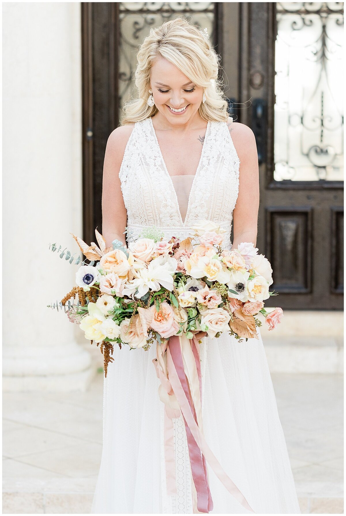 Bride standing in front of ornate door with white and pink bouquet