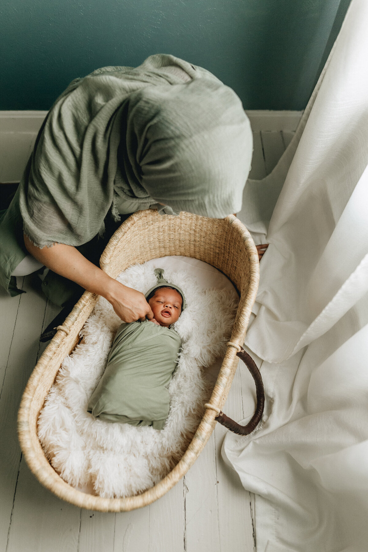Mom watching over her newborn baby sleeping in a crib.
