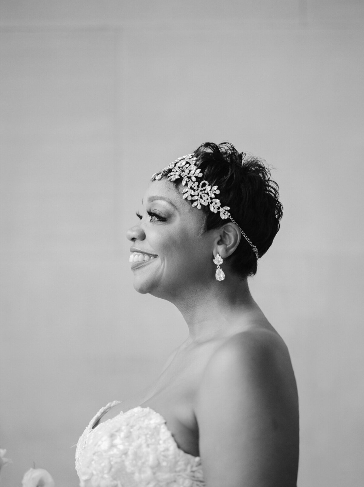 side profile of beautiful black bride with crystal headpiece, earrings, lace strapless gown