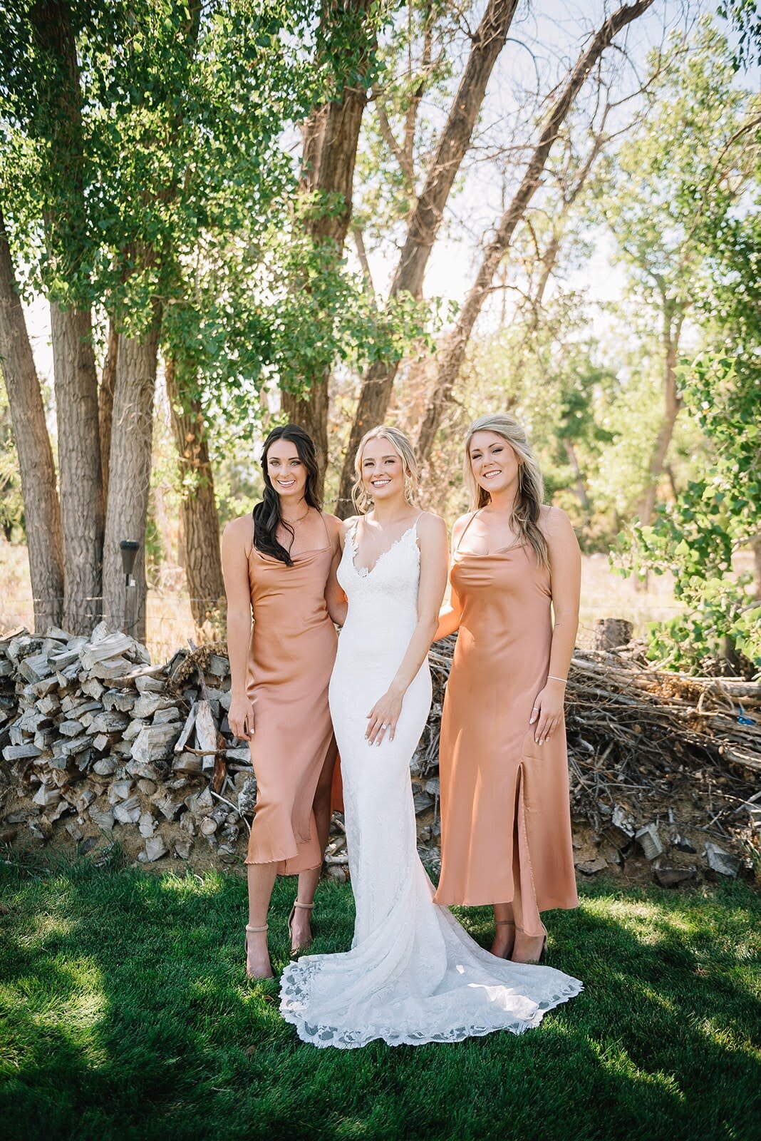 Bride poses with her bridesmaids in light orange dresses.