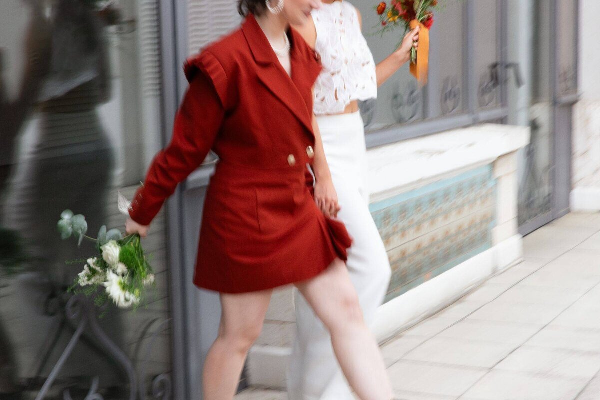 Photographie en flou artistique de deux mariées lgbtqia+ qui sortent de la mairie après leur cérémonie civile à Le Grand-Lemps