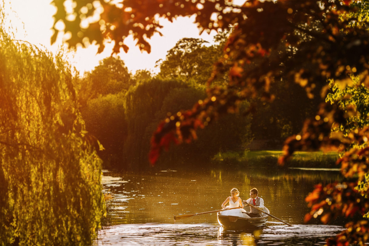 Bride and groom on a rowing boat during golden hour at Browsholme Hall