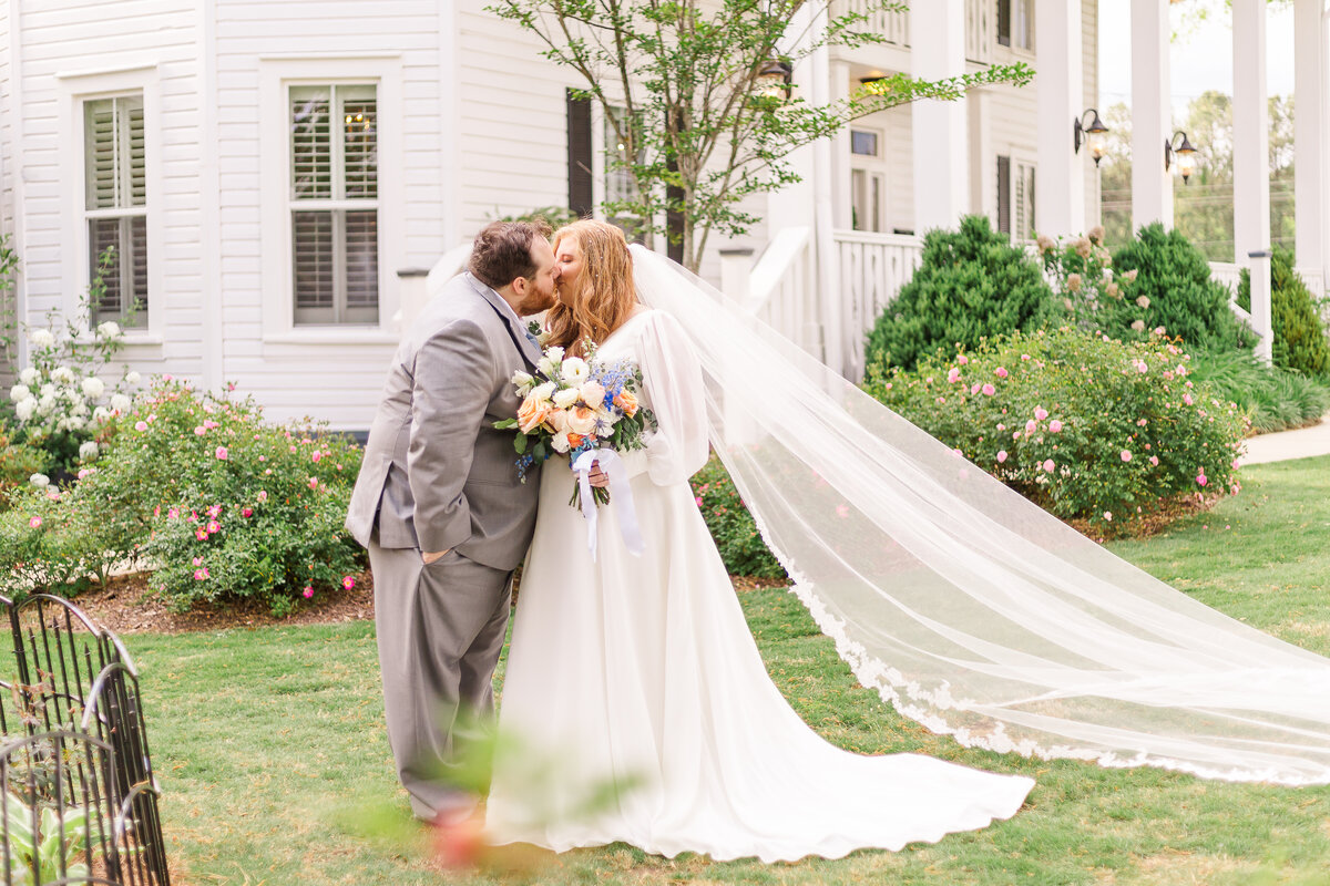 Bride and groom kiss while standing in front of wedding venue