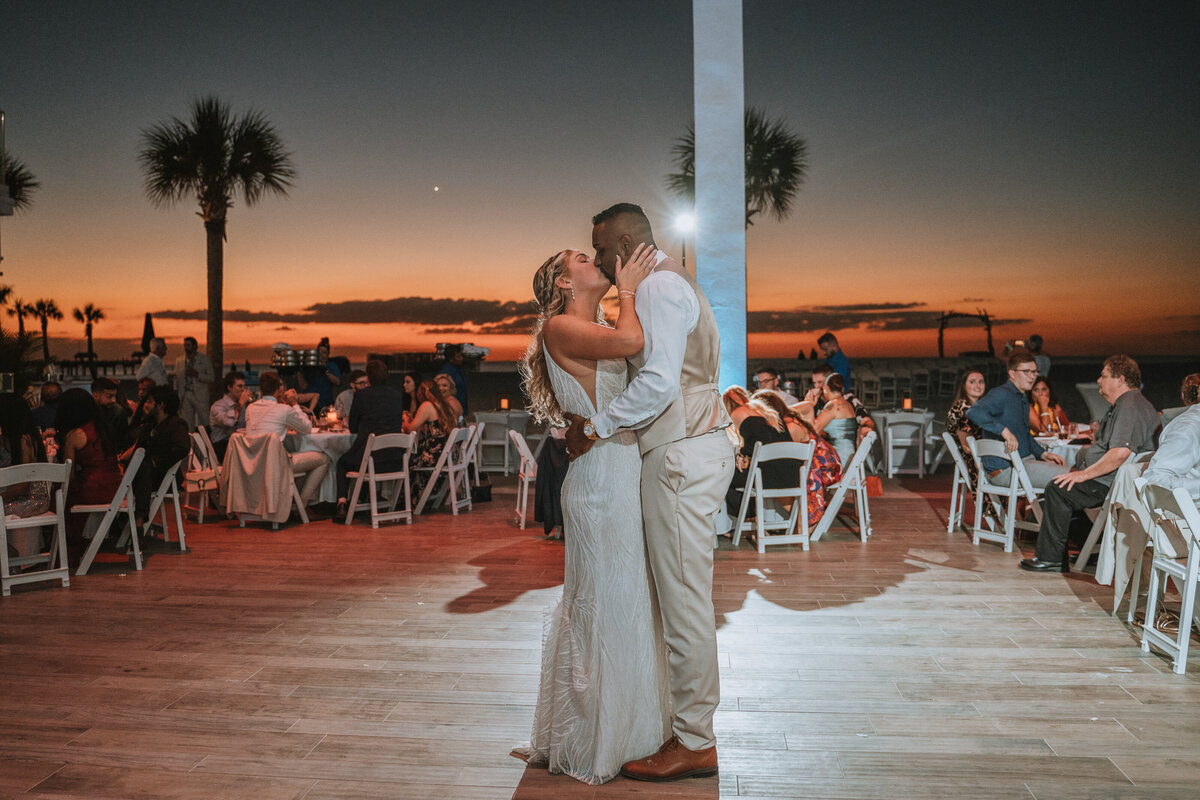 bride and groom share kiss after first dance while sun is setting  on st pete beach