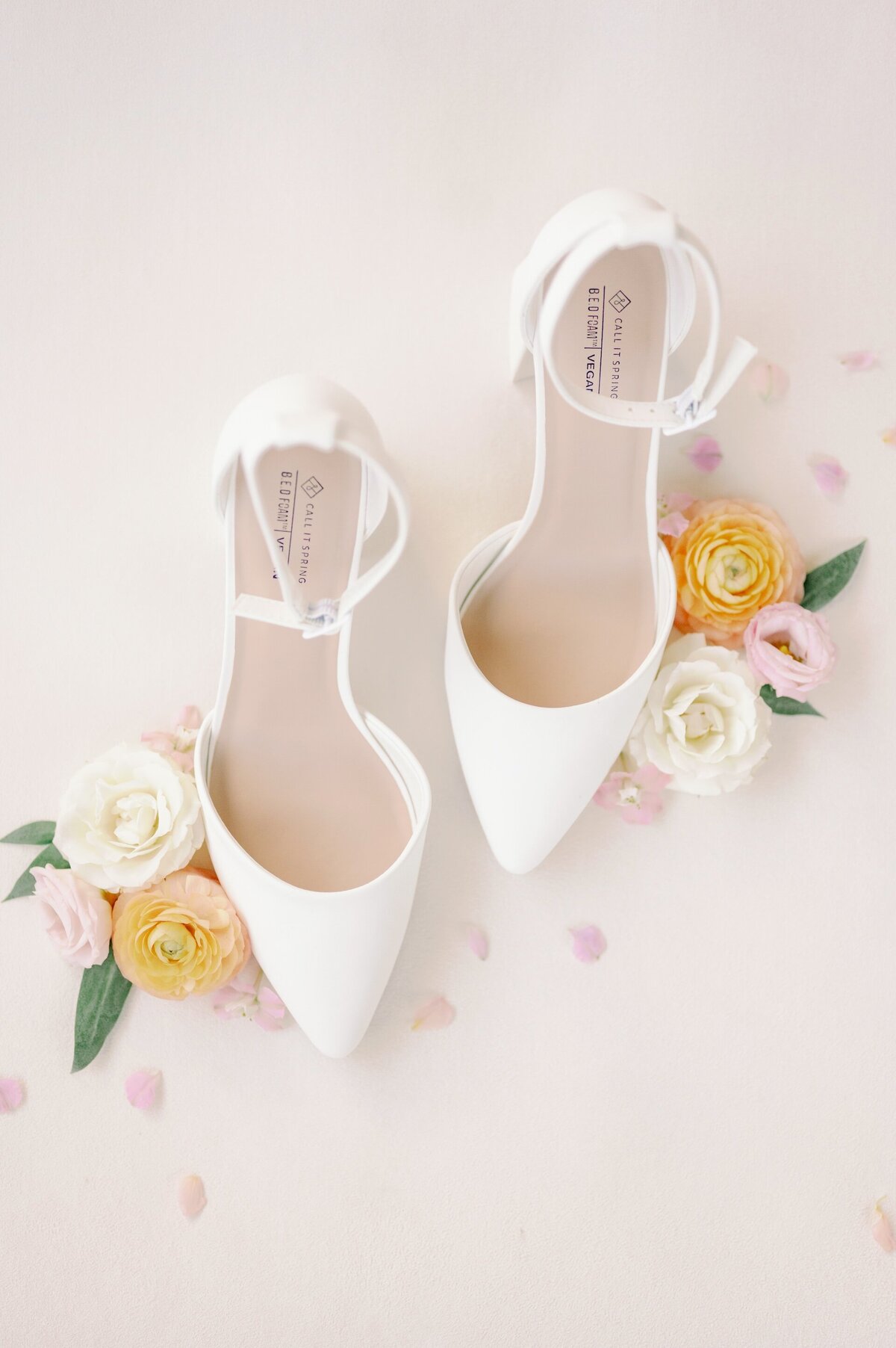 white bridal shoes surrounded by colorful flowers