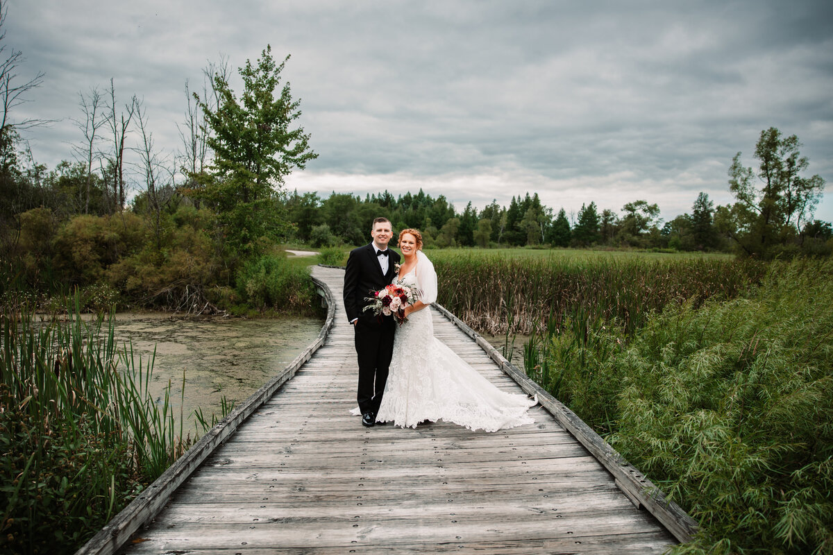 Newlyweds Walk on a wooden bridge on a lake while smiling