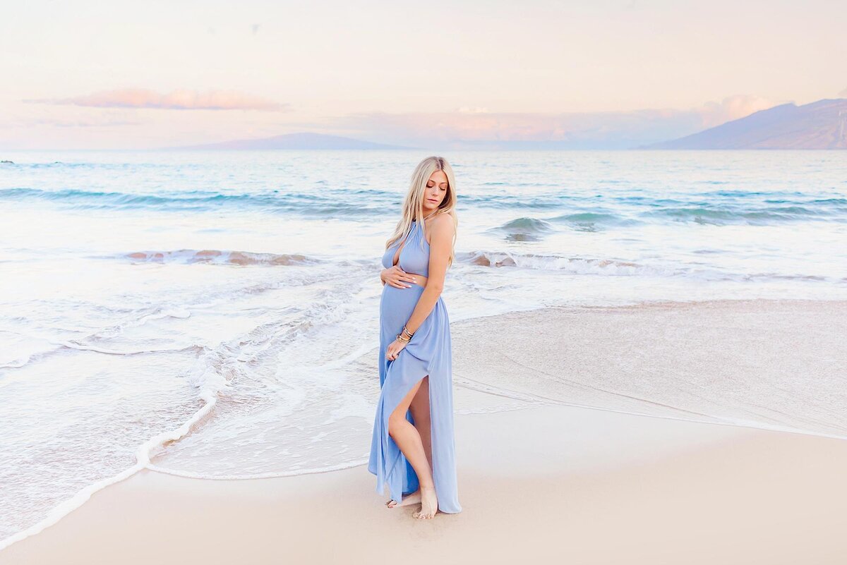 Pregnant model holds her belly outside the Four Seasons in Wailea for her babymoon portraits on Maui with Love + Water