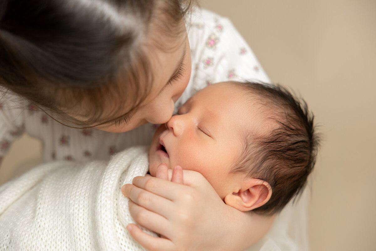 Edmonton studio portraits young girl holding her newborn wrapped baby brother