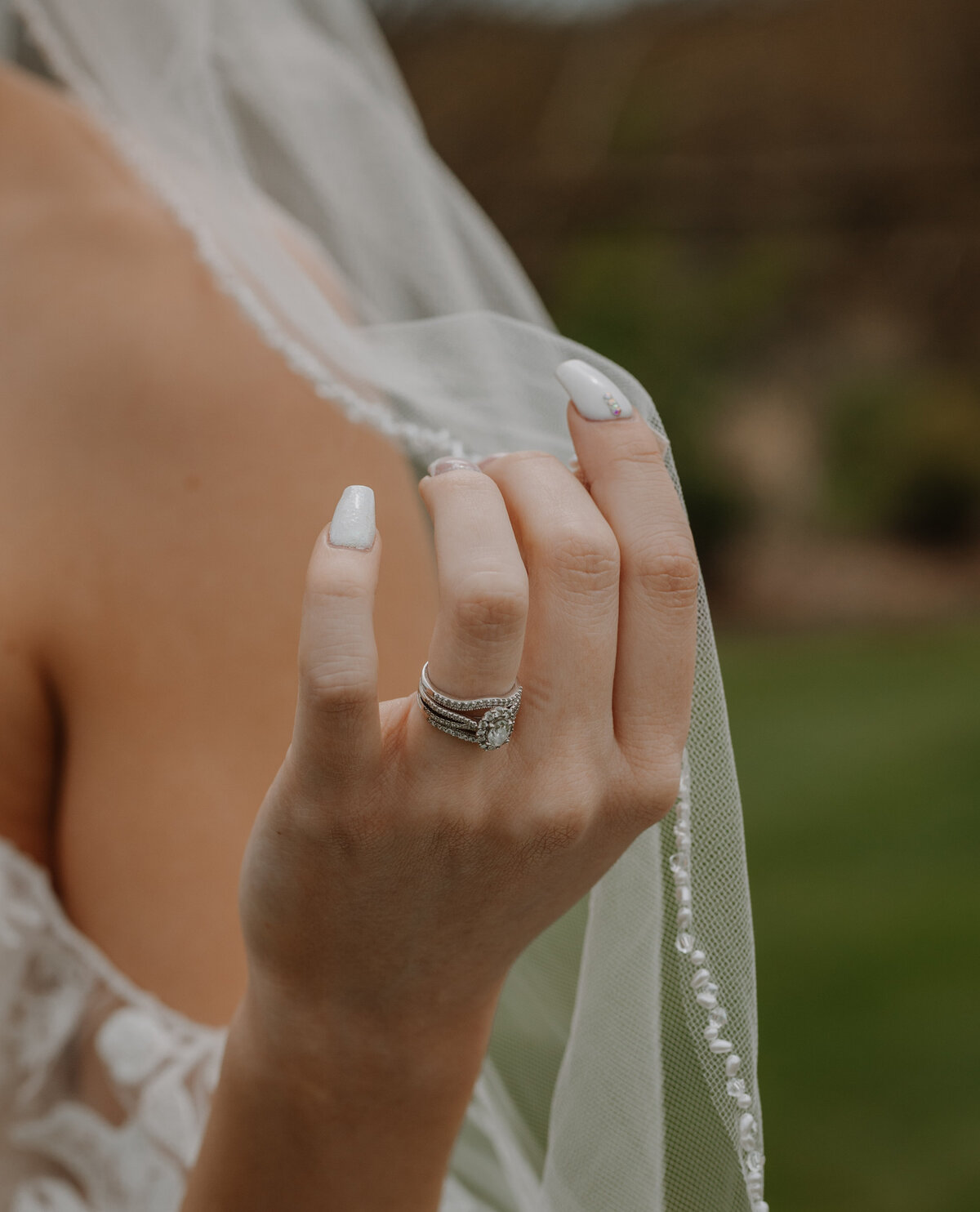 Bride holding veil with wedding ring
