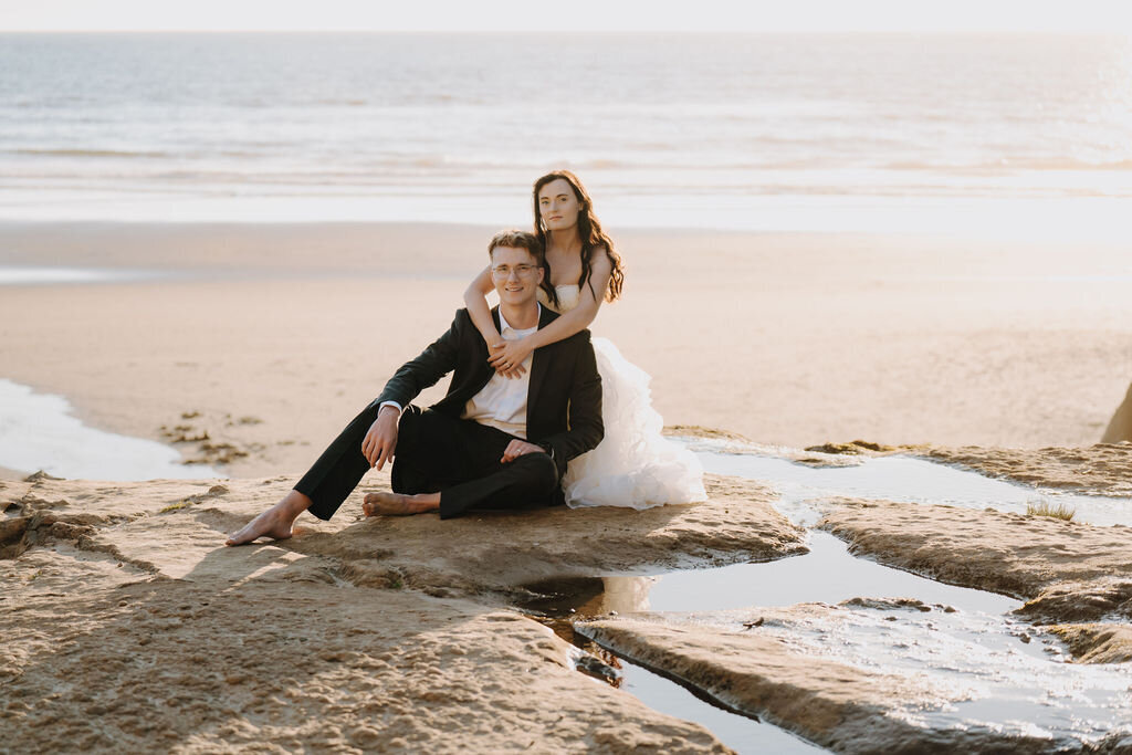 a man and woman in wedding attire posing on the beach