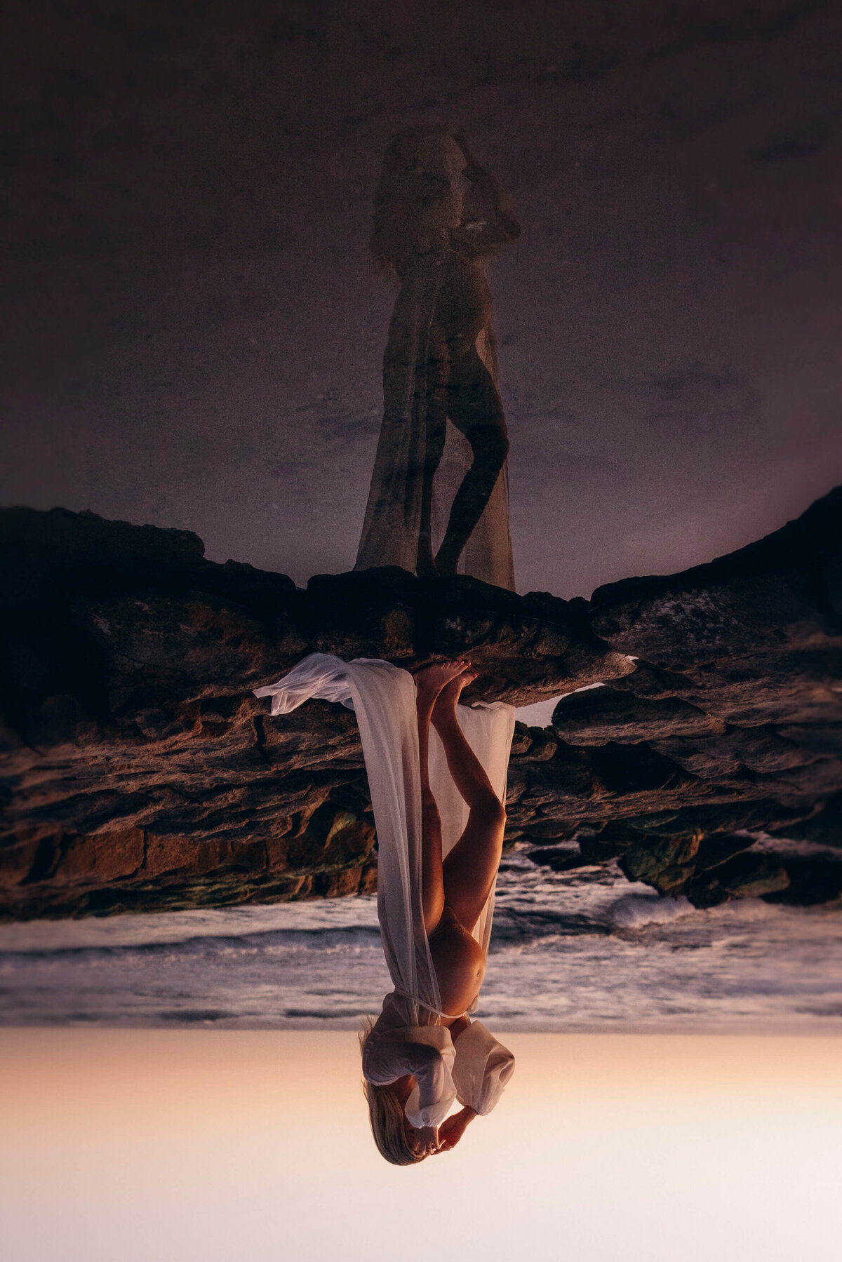 pregnant woman standing on rocks on the beach
