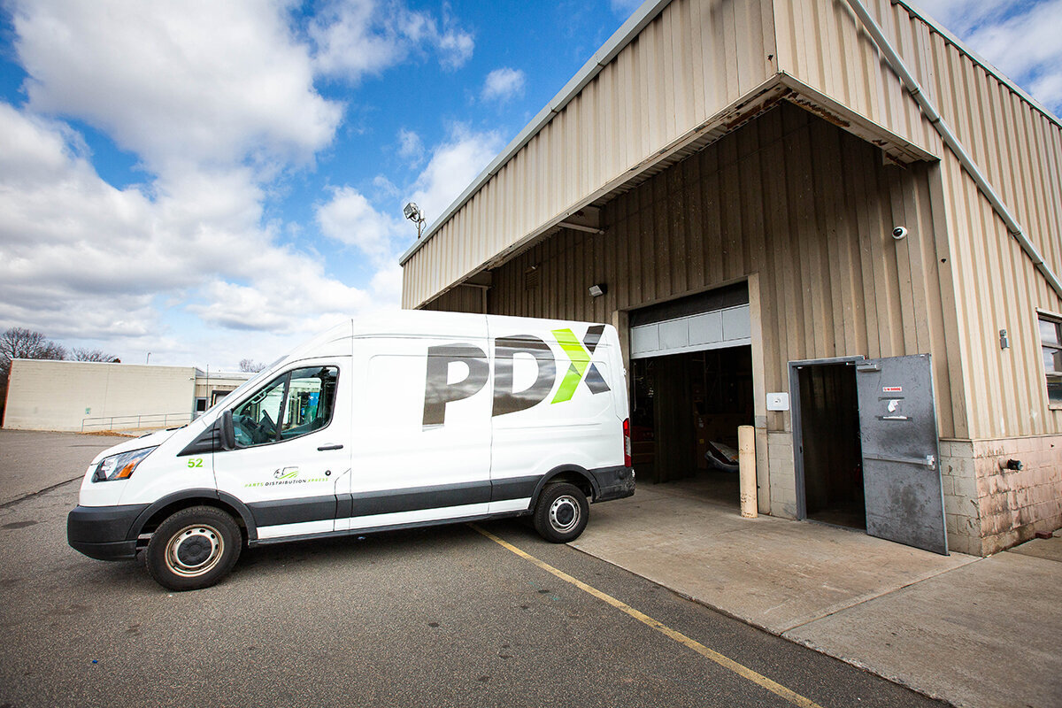 white van with the letters PDX on it parked in front of an industrial building