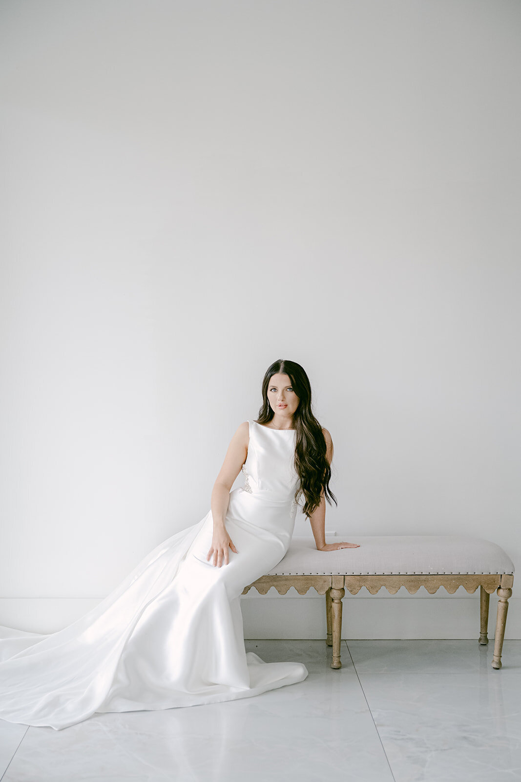 Bride in satin gown seated softly in a minimalist white room at The Videre Estate, captured by Austin wedding photographer, Erin Marcin.