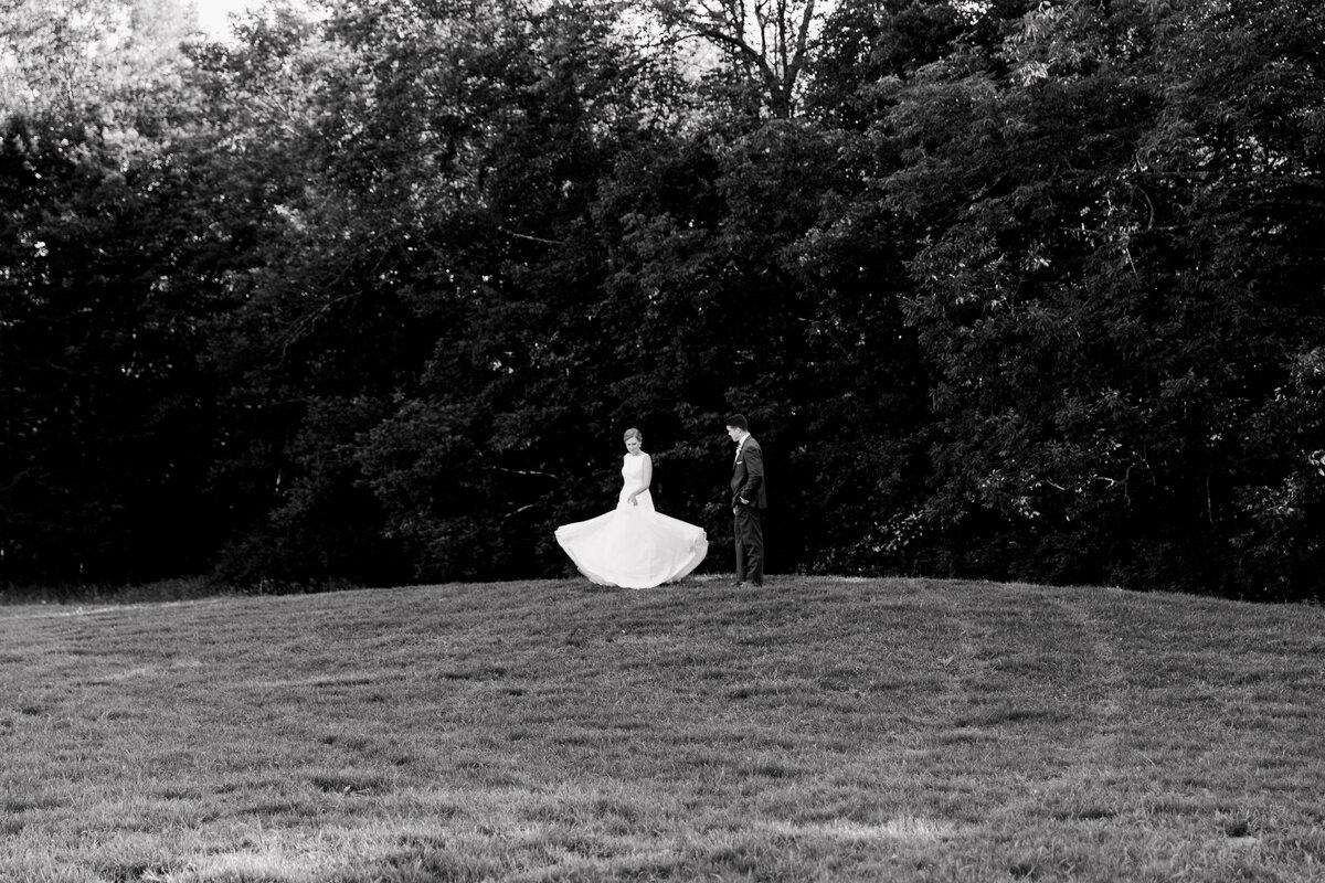 Black and white photo of a bride and groom dancing in a grassy field