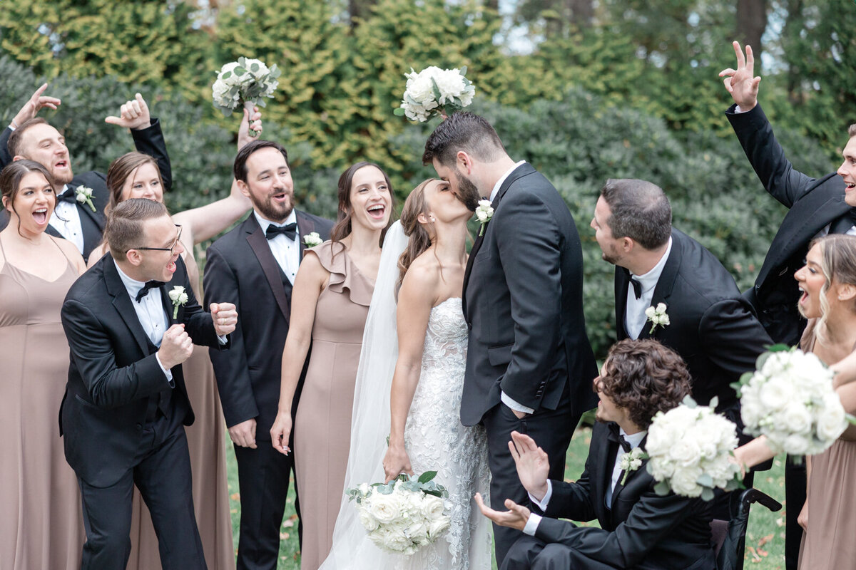 Tyhe wedding party celebrates at the Avenir as the bride and groom kiss