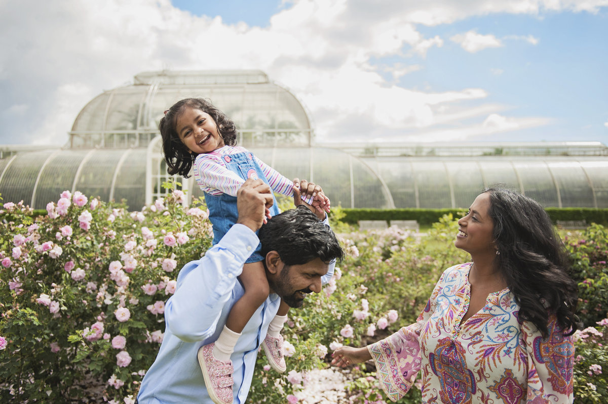 A little girl laughs on her father's shoulders at Kew Gardens