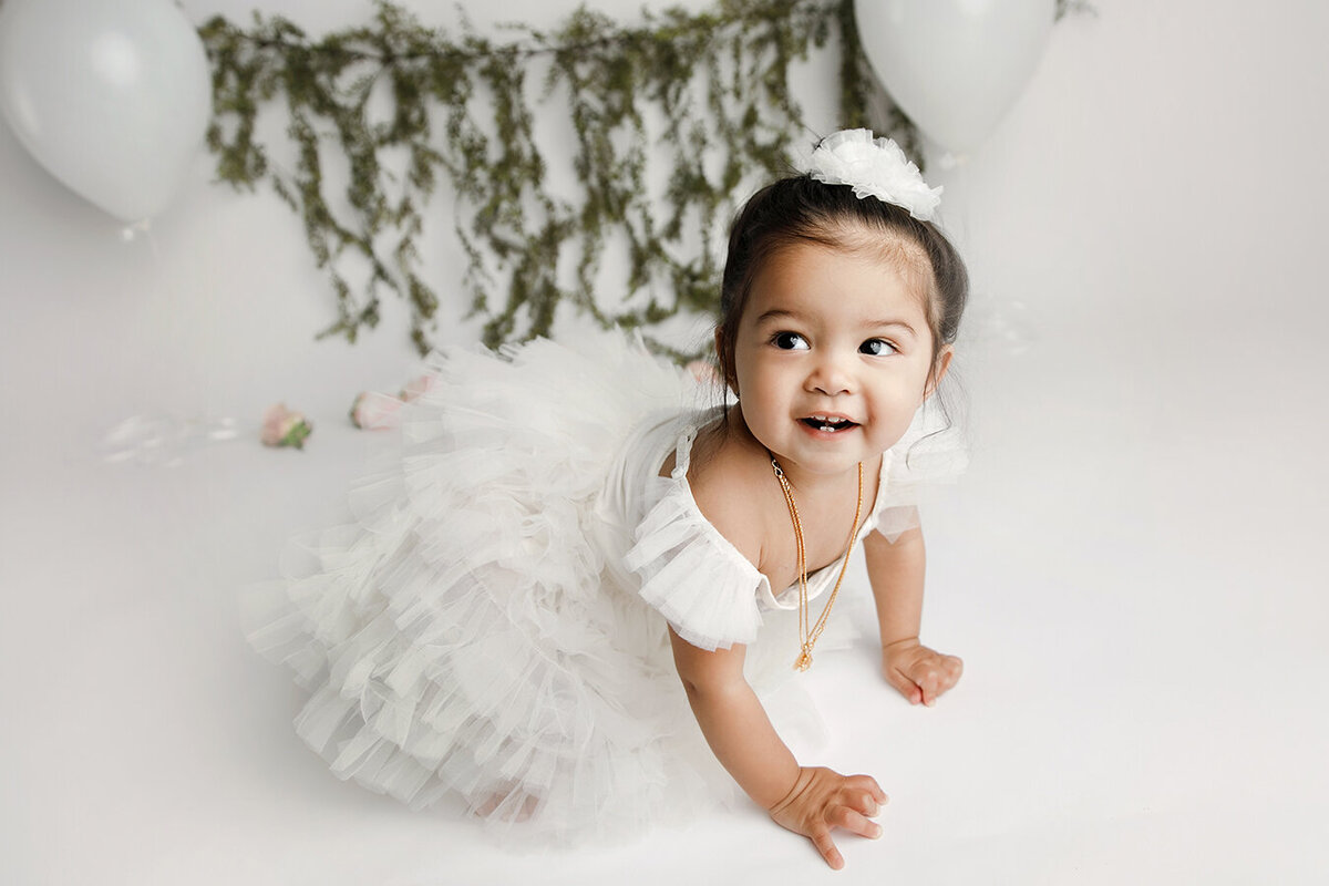 Beautiful one year old in white dress smiling