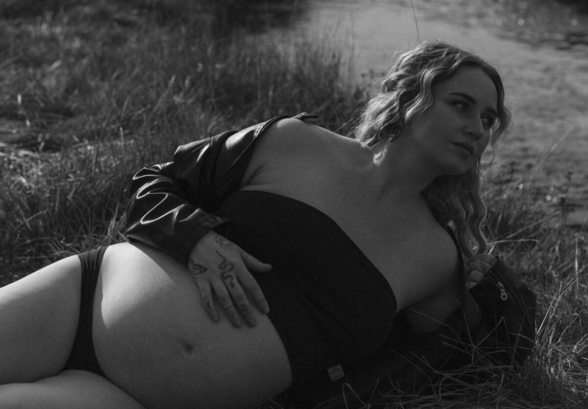 mother to be poses with her hand on her belly in a field in Bend, Oregon