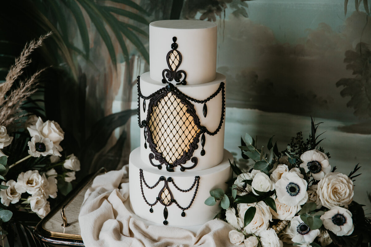Gorgeous and elegant white wedding cake with black lace icing detail, by Yvonne's Delightful Cakes, classic cakes & desserts in Calgary, Alberta, featured on the Brontë Bride Vendor Guide.
